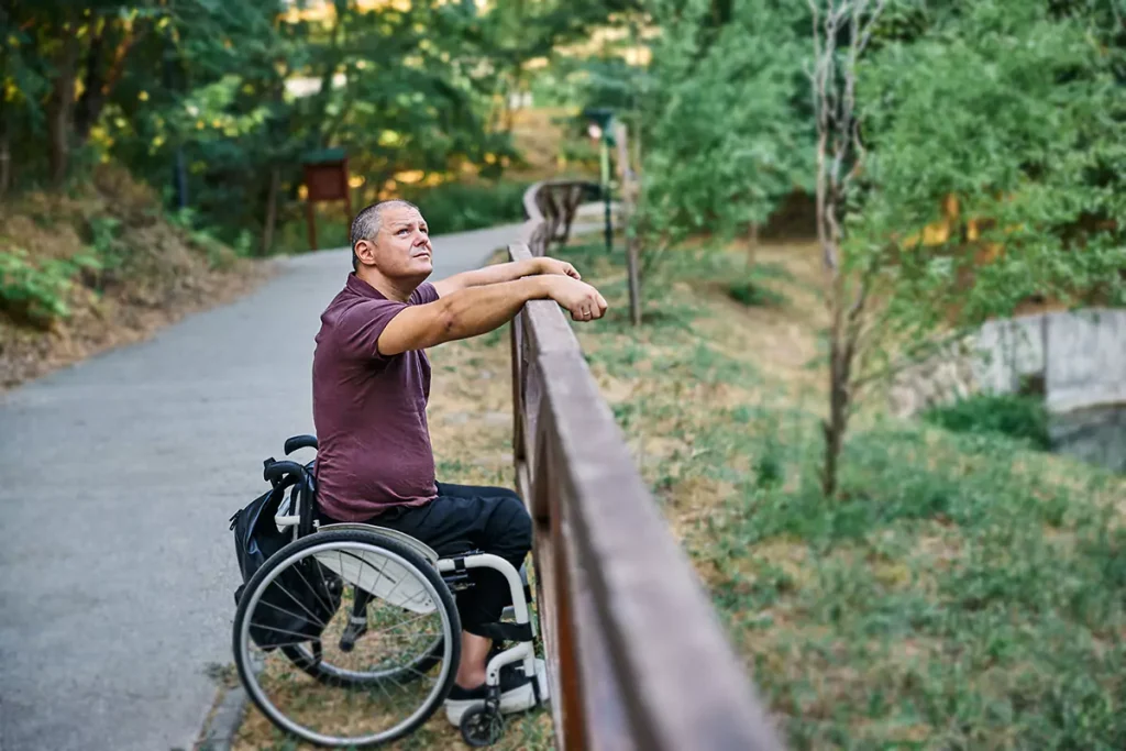 A disabled man sitting in his wheelchair outdoors looking at the sky